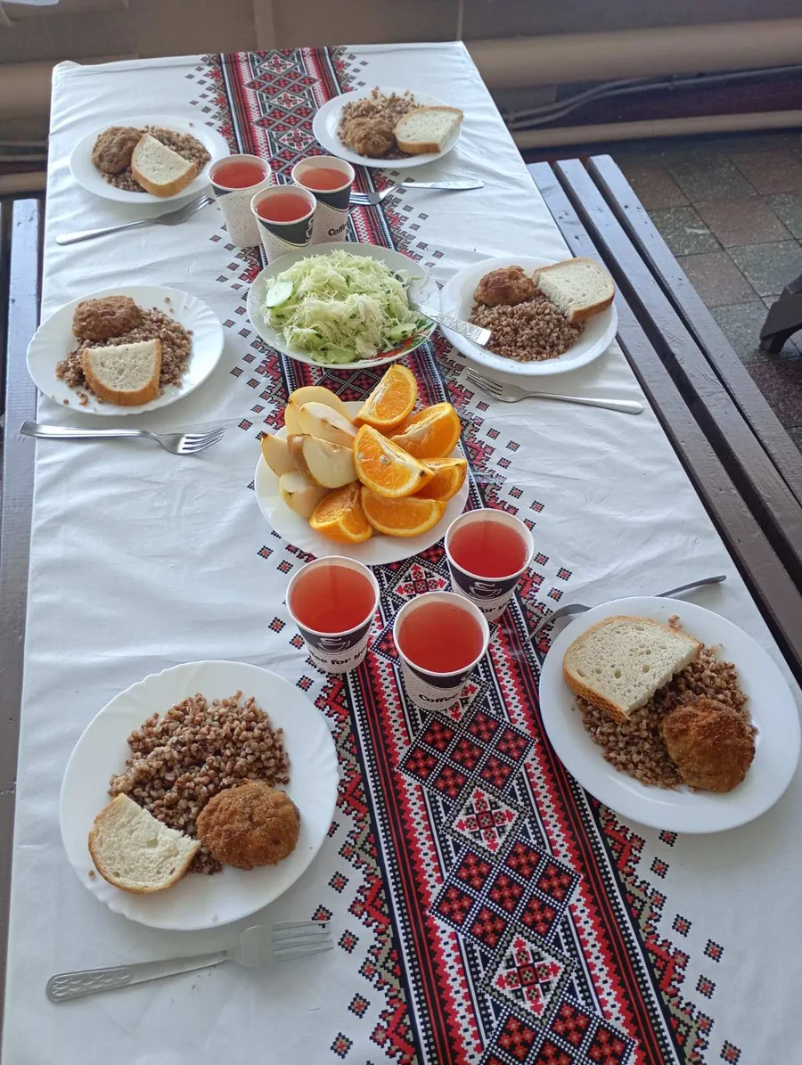Порції гречки з котлетою, хлібом, салатом, фруктами та напоєм на столі