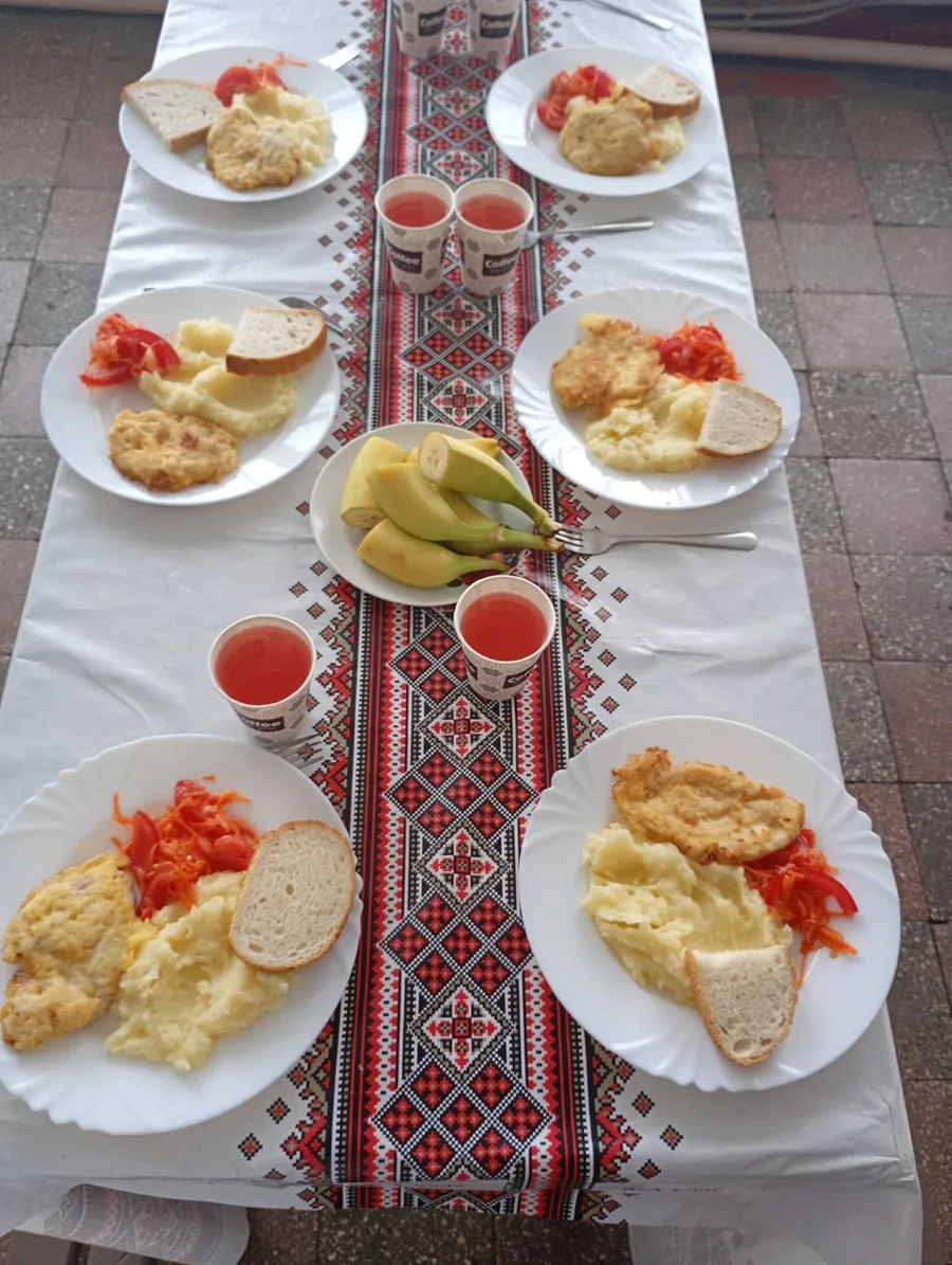 Порції картопляного пюре з відбивною, овочами, хлібом, бананами та напоєм